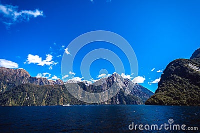 Beautiful panorama of Milford Sound with Mitre Peak on the foreground and snow capped mountains in the background taken on a sunny Stock Photo