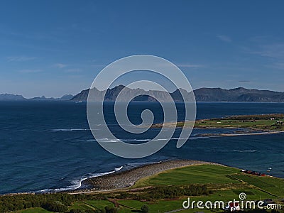 View of the northern coast of Lofoten, Norway on the shore of Norwegian Sea with rocky beach, fields and mountains of island. Stock Photo
