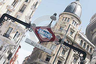 Beautiful photograph of the sign of the subway entrance of the metro of madrid GRAN VIA with its buildings Editorial Stock Photo