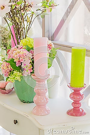 Beautiful pink flowers in green vase and Candles on white wooden commode Stock Photo