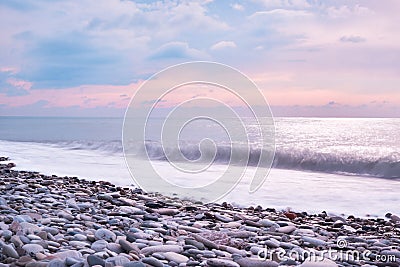 Beautiful sea landscape. Beautiful pink sunset sky over sea coast with pebble beach. Photo is frozen using long shutter speed Stock Photo