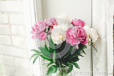 Beautiful pink and white peonies bouquet at rustic old wooden window. Floral decor and arrangement. Gathering flowers. Rural still Stock Photo