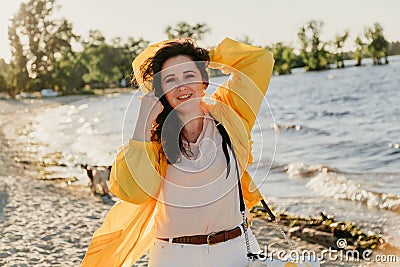 Beautiful plus size woman in yellow jacket on sandy shore Stock Photo