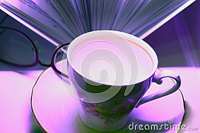 Beautiful porcelain Cup on a saucer with a book and reading glasses Stock Photo