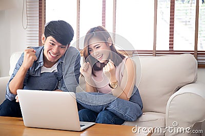 Beautiful portrait asian young couple working laptop with smile and happy sitting on couch at living room Stock Photo