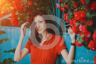 Beautiful portrait of sensual brunette woman close to red roses. Toned image Stock Photo