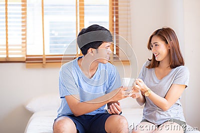 Beautiful portrait young asian couple give a cup of coffee with smiling and happy together Stock Photo