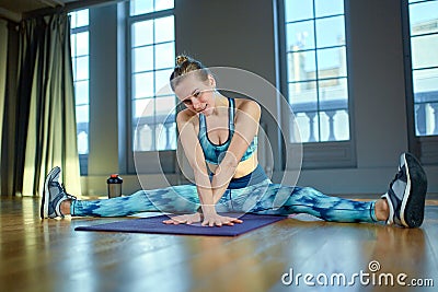 Beautiful portrait of young woman relaxing form exercise and smiling during a break in the gym. Caucasian female sitting Stock Photo