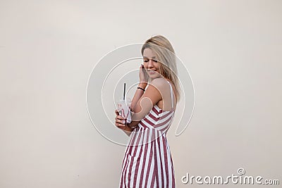 Beautiful positive pretty young woman with a cute smile in a trendy pink summer dress with stripes with a milky sweet cocktail Stock Photo