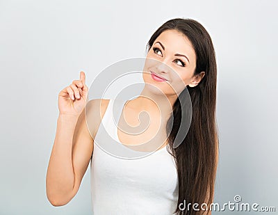 Beautiful positive young happy woman with hand under the face thinking and looking up in casual white t-shirt and long hair on Stock Photo