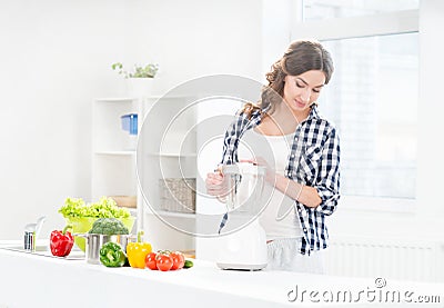 Beautiful pregnant smiling woman cooking with a blender Stock Photo