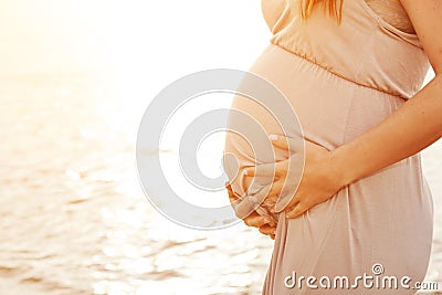 A beautiful pregnant woman on the beach touching her belly Stock Photo