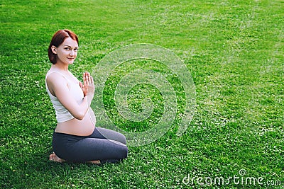 Beautiful pregnant woman doing prenatal yoga on nature outdoors. Stock Photo