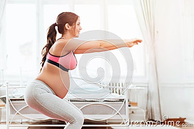 Beautiful pregnant woman excercising in a bright room Stock Photo