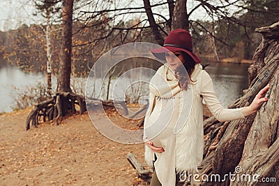 Beautiful pregnant woman in fashion hat on cozy warm outdoor walk Stock Photo