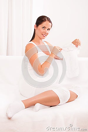 Beautiful pregnant woman holding baby clothes Stock Photo