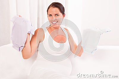 Beautiful pregnant woman holding baby clothes- bodysuits Stock Photo