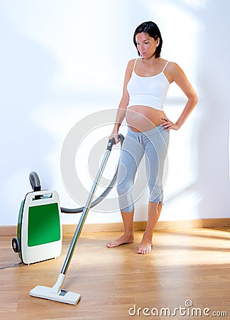 Beautiful pregnant woman retro vacuum housewife Stock Photo