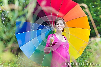 Beautiful pregnant woman walking under colorful umbrella Stock Photo