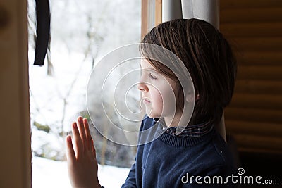 Beautiful preteen child in a little fancy wooden cottage, looking out of the window Stock Photo