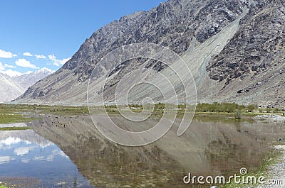 A beautiful, pristine, calm lake view, kissing the foot of the mountains and running along the road side. Stock Photo