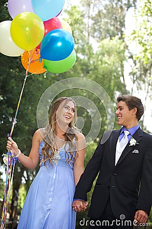 Beautiful Prom Couple Walking with Balloons Outside Stock Photo