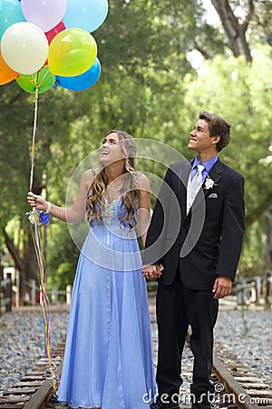 Beautiful Prom Couple Walking with Balloons Outside Stock Photo