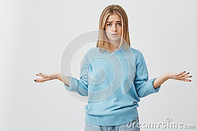 Beautiful puzzled and confused young woman dressed casually exclaming in despair and shrugging shoulders in full Stock Photo