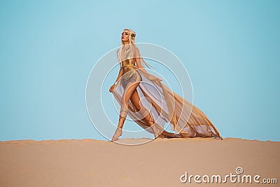 Beautiful queen of the desert in a luxurious gold dress. Stock Photo