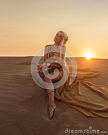 Beautiful queen of the desert in a luxurious gold dress. Stock Photo