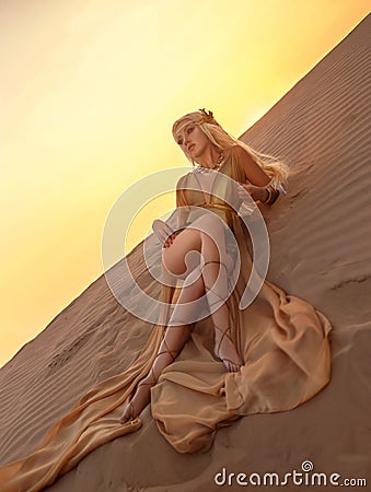 Beautiful queen of the desert in a luxurious gold dress. Stock Photo