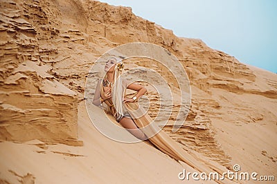 Beautiful queen of the desert in a luxurious gold dress. Stock Photo