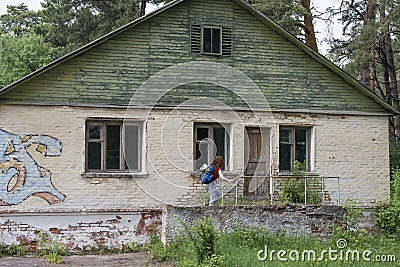 Beautiful red hair woman tourist with backpack exploring abandoned summer camp Stock Photo