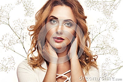 Beautiful redhaired girl in white dress with a gentle romantic make-up and flowers. The beauty of the face. Stock Photo