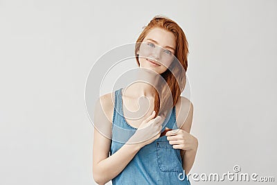 Beautiful redhead girl with freckles smiling touching hair. Stock Photo