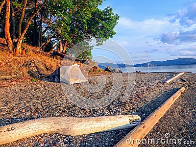 A beautiful remote camping location on a sandy beach along the ocean beside the forest. It is a sunny summer evening Stock Photo