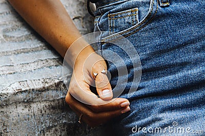 A beautiful ring on the finger of a young girl dressed in denim jeans and sitting on a stone wall Stock Photo