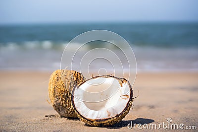 Beautiful ripe coconut the lake broken down into 2 half lies on a white sand beach Stock Photo