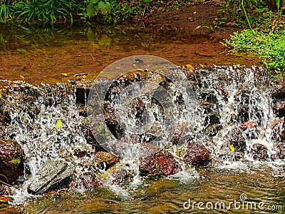 Beautiful view of waterfalls and lakes, amidst rocks, tree trunks, vegetation and woods. Stock Photo