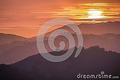 Beautiful rolling hills bathed in the sunset light; the setting sun reflected in the water of the San Francisco Bay in the Stock Photo