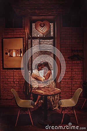 Beautiful romantic couple dating in cafe. Young lovers hugging and kissing at table. Authentic Love date Stock Photo