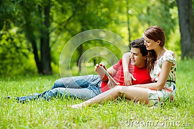 Beautiful romantic couple with tablet pc at summer green park Stock Photo