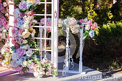 Beautiful romantic festive place made with wooden arch and flowers decorations for outside wedding ceremony in summer garden. Gaze Stock Photo