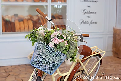 Beautiful romantic landscape: vintage wicker basket with flowers near the cafe. Old bicycle with flowers in a metal basket on the Stock Photo