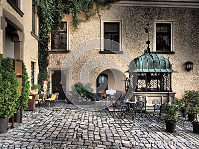 Old iron well on a historic castle background where there are trees amd flowers Stock Photo