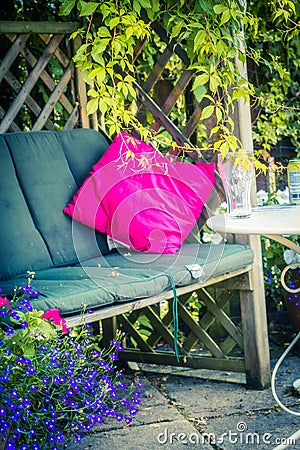 Beautiful, romantic seat in the garden with pink cushion and climbing ivy. Stock Photo