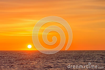 Beautiful round and bright sun setting against a vivid orange sk Stock Photo