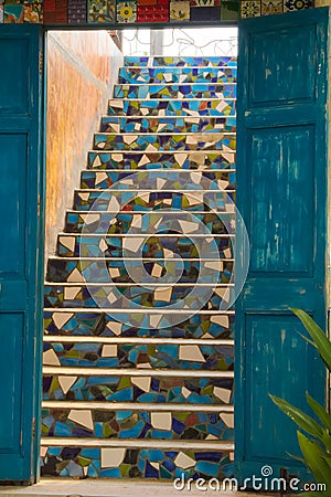 A beautiful rustic blue wooden set of doors, leading up to a lovely tiled stairway, in a very creative seaside restaurant. Stock Photo