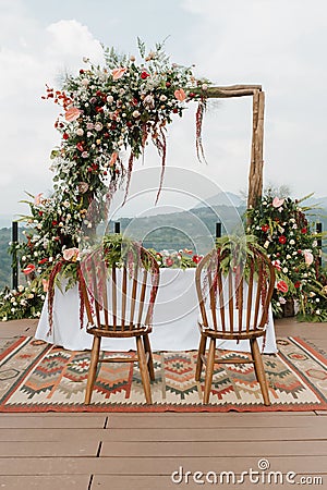Beautiful rustic theme outdoor wedding white altar setup, with natural flower decoration and mountain background Stock Photo