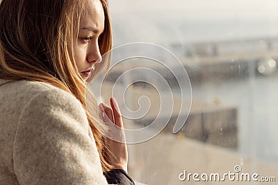 Beautiful sad lonely girl sitting near the window is missing Stock Photo
